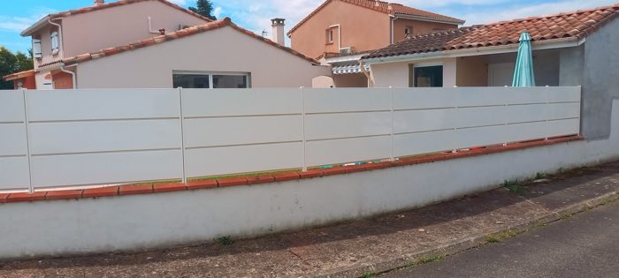 Clôture occultante à lames horizontales blanches, posée en rehausse sur un mur de séparation
